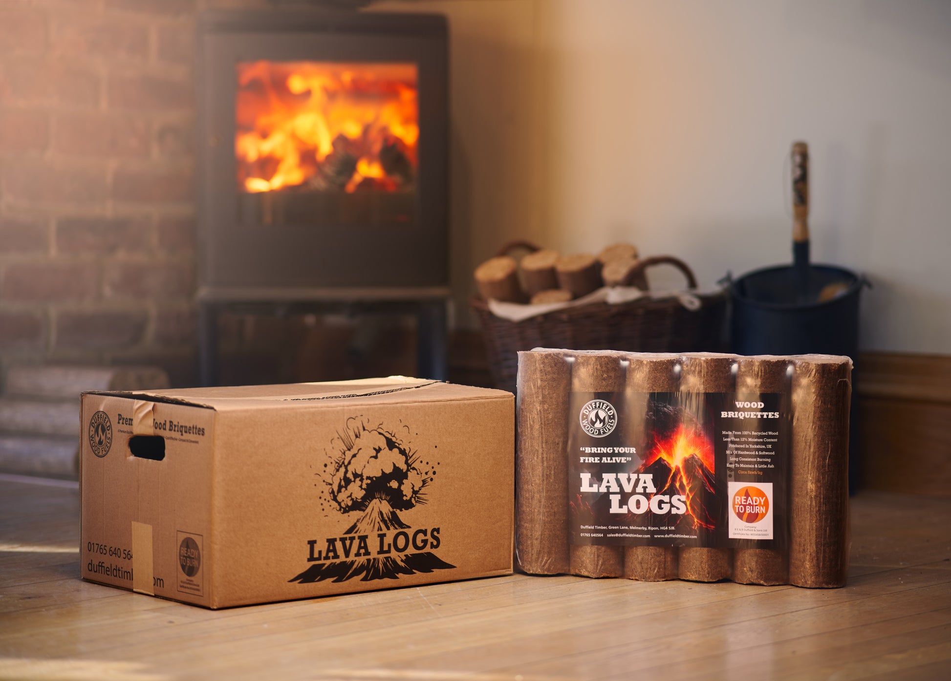 A box and pack of Lava Log wood briquettes positioned in front of a roaring fire